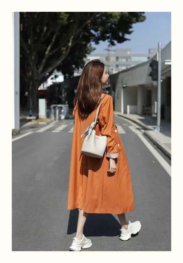 Model wearing a genuine leather handbag, showcasing the beige bucket bag against a lively street backdrop, perfectly combining fashion and function.