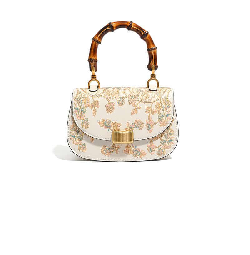 Stylish Cowhide Leather Handbag with Exquisite Embroidery and Bamboo Handles for Women - Front view of a cream-colored cowhide leather handbag featuring intricate embroidery and a bamboo handle.