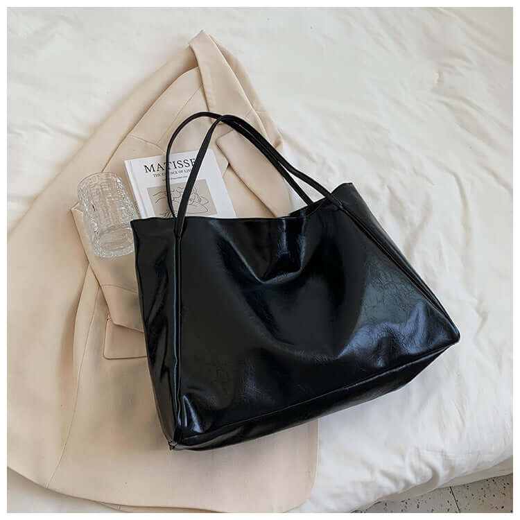 Fashion Handbag New Autumn And Winter Japanese And Korean Large Capacity Soft Leather Shoulder Bag featured in sleek black color atop a white bedding.