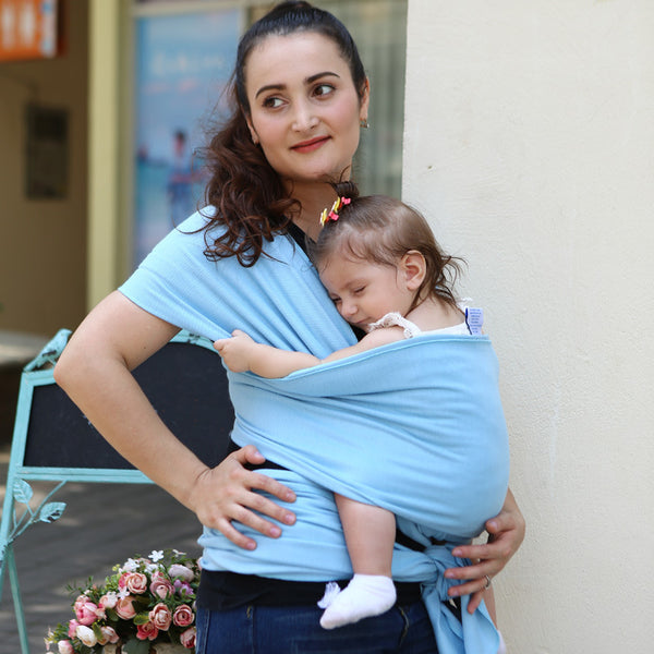 Mother with baby using a baby sling solid color baby carrier in light blue, demonstrating comfort and support.