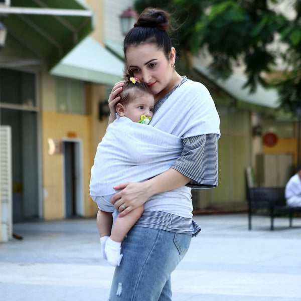 Mom carrying her baby in a gray baby sling solid color baby carrier, showcasing convenience for parents.