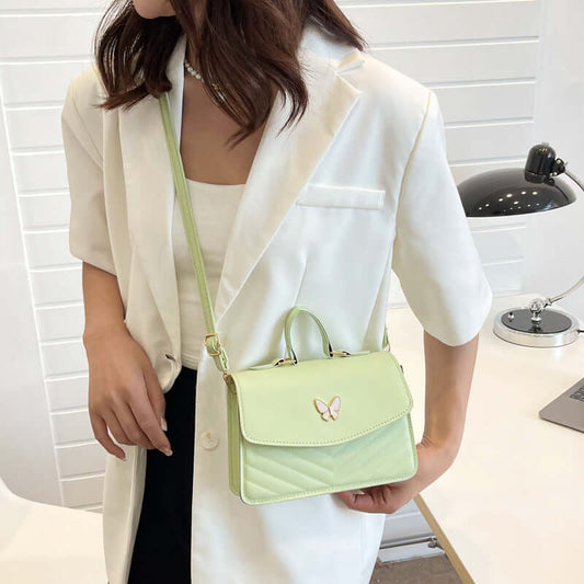 Mint green Simple Crossbody Bag with butterfly clasp top handle and adjustable strap styled on woman in white blazer