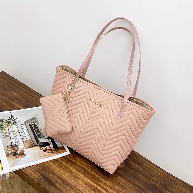 Stylish Women's Shoulder Bag with Wave Pattern Diamond Plaid Embroidery in pink, showcasing a fashionable shoulder bag placed on a wooden table near a magazine.
