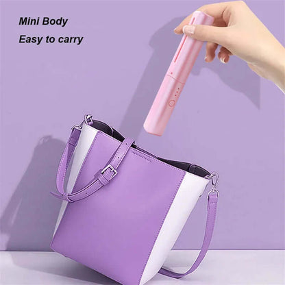 Pink cordless hair straightening brush being placed into a purple and white handbag showing its mini body and portability