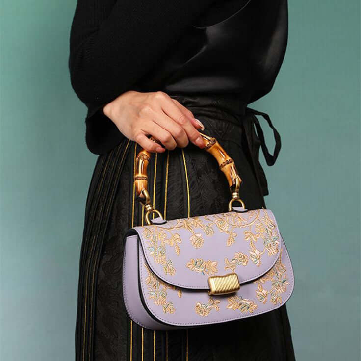 Stylish Cowhide Leather Handbag with Exquisite Embroidery and Bamboo Handles for Women - Model displaying a lavender cowhide leather handbag featuring exquisite embroidery and bamboo handles.