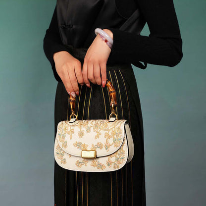 Stylish Cowhide Leather Handbag with Exquisite Embroidery and Bamboo Handles for Women - Model holding a cream-colored cowhide leather handbag with exquisite embroidery and bamboo handles.