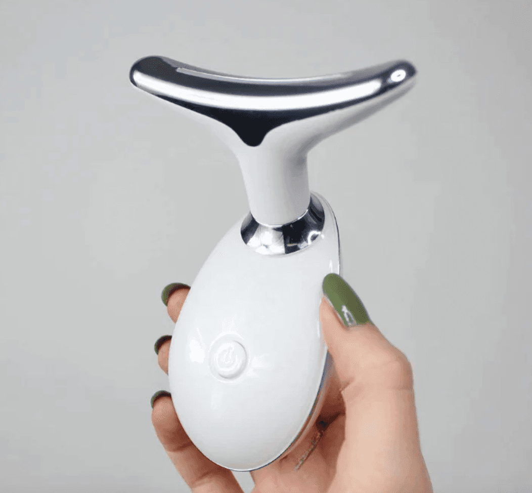 The Pure Aura Micro Glow Massager held in a person's hand against a neutral backdrop, emphasizing its ergonomic design and ease of use in achieving glowing skin. Part of the lumiglow, lumiglow pro collection.