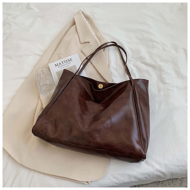 Fashion Handbag New Autumn And Winter Japanese And Korean Large Capacity Soft Leather Shoulder Bag presented in rich brown color on a light fabric.