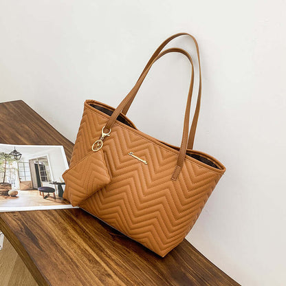 Chic Women's Shoulder Bag with Wave Pattern Diamond Plaid Embroidery in light brown, representing a fashionable shoulder bag set on a wooden table next to a magazine.