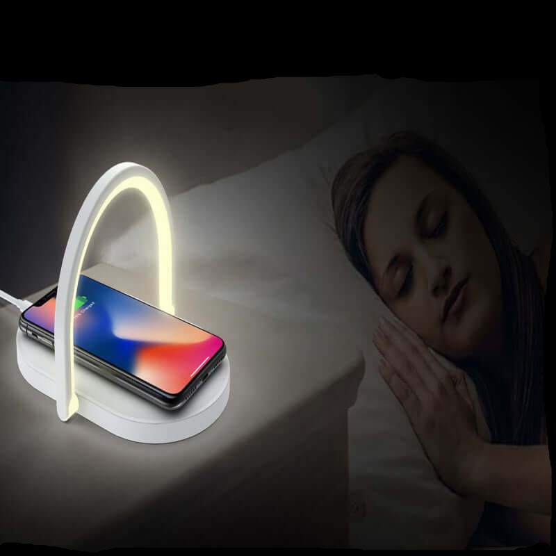 Fast wireless charger with night light charging smartphone next to sleeping woman on bed