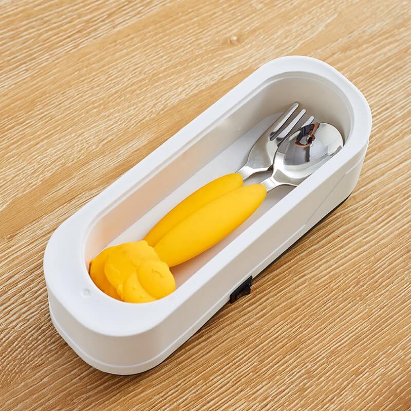 CozyTech Living ultrasonic eyeglasses cleaner with white case on wooden surface holding spoon and fork