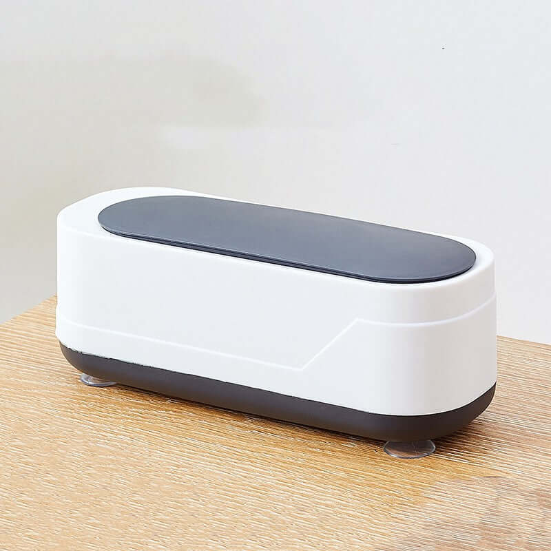 CozyTech Living ultrasonic eyeglasses cleaner in white and black on wooden surface