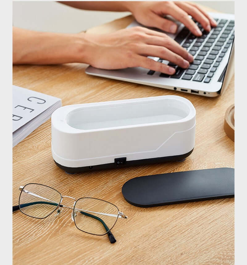 CozyTech Living ultrasonic eyeglasses cleaner on desk next to glasses and laptop in use