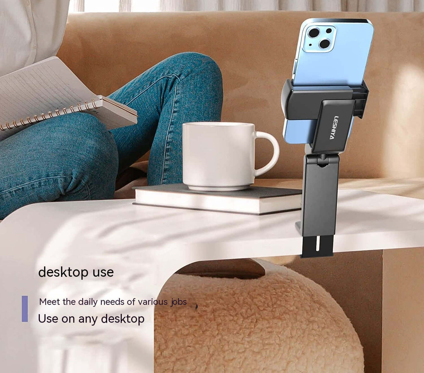 Foldable phone holder for travel clipped on a desk holding a blue smartphone next to a coffee cup