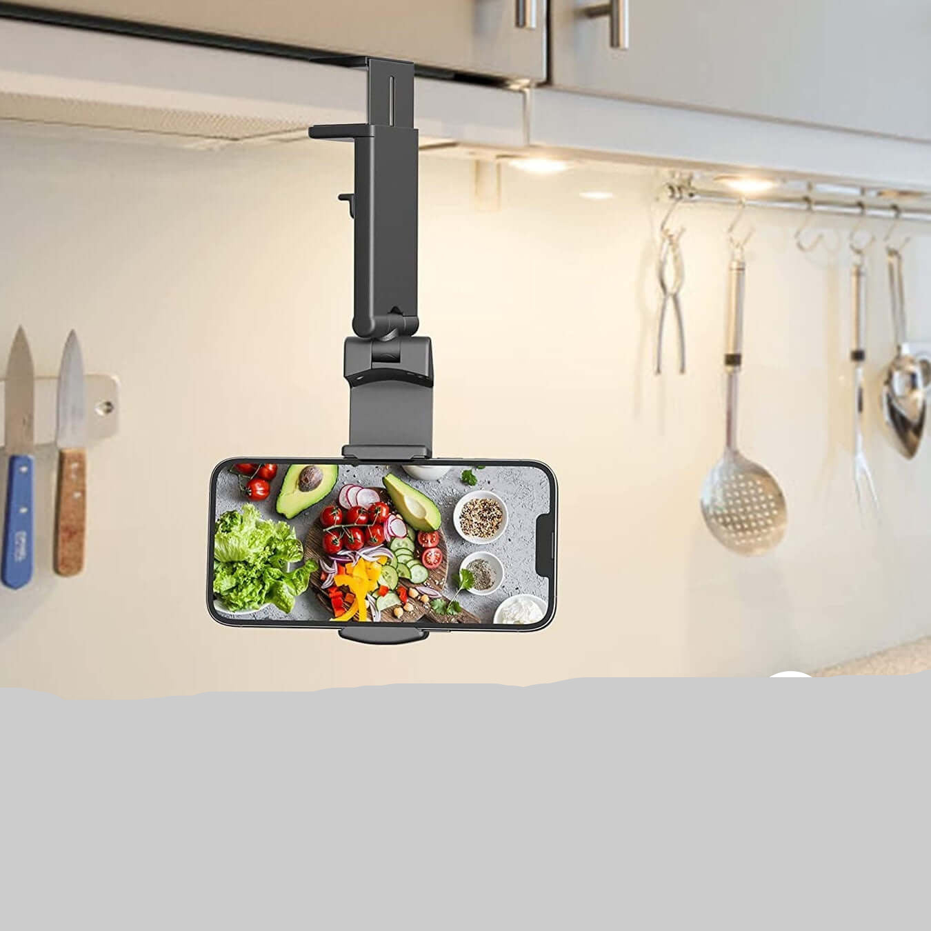 Black foldable phone holder for travel clipped under kitchen cabinet holding smartphone horizontally