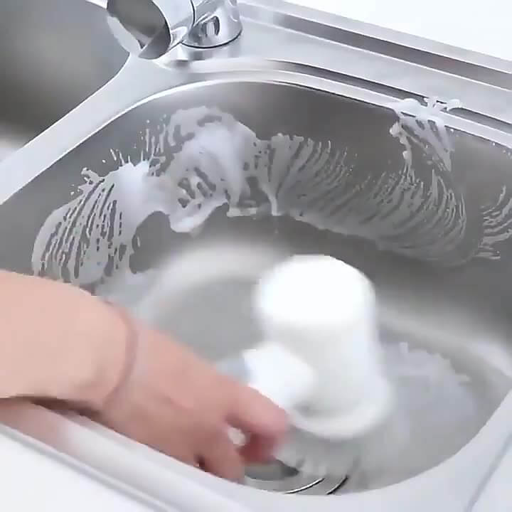 Person using powerful cleaning brush for kitchen to scrub a stainless steel sink with soap foam