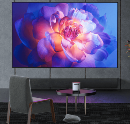 Smart projector for living room displaying a vibrant flower image on a large wall screen above a modern chair and table