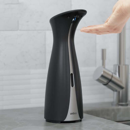 Black and silver modern induction hand soap dispenser on bathroom counter with hand underneath